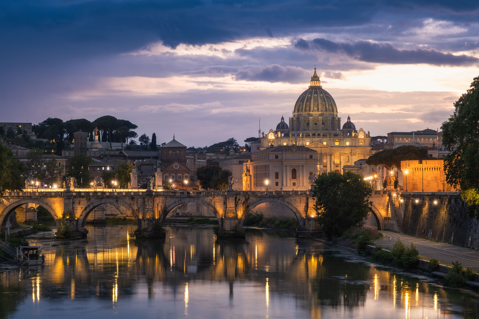 View of the Vatican City at sunset. The main building, St. Peters Basilica stands illuminated across theTiber River