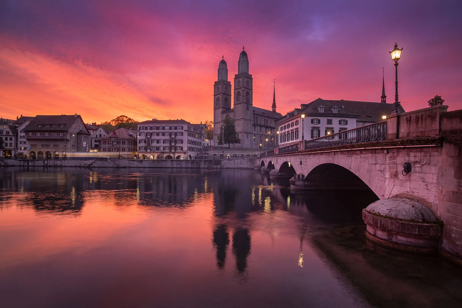 View of Grossmünster church and Münsterbrücke, the bridge connecting both sides of the Old Town in Zurich. Taken on a special morning when the high clouds caught the first light of the rising sun.